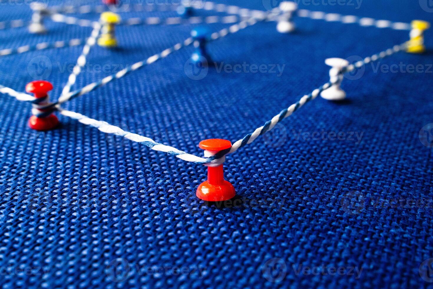 Network visualization with colored pins and string on blue fabric, connection concept photo