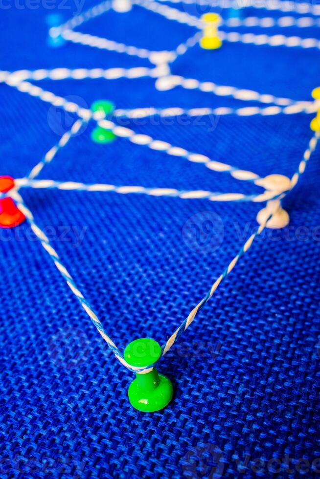 Network visualization with colored pins and string on blue fabric, connection concept photo