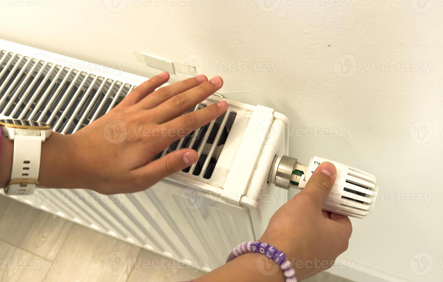 hand adjusting radiator temperature using thermostat. Home with central heating. photo