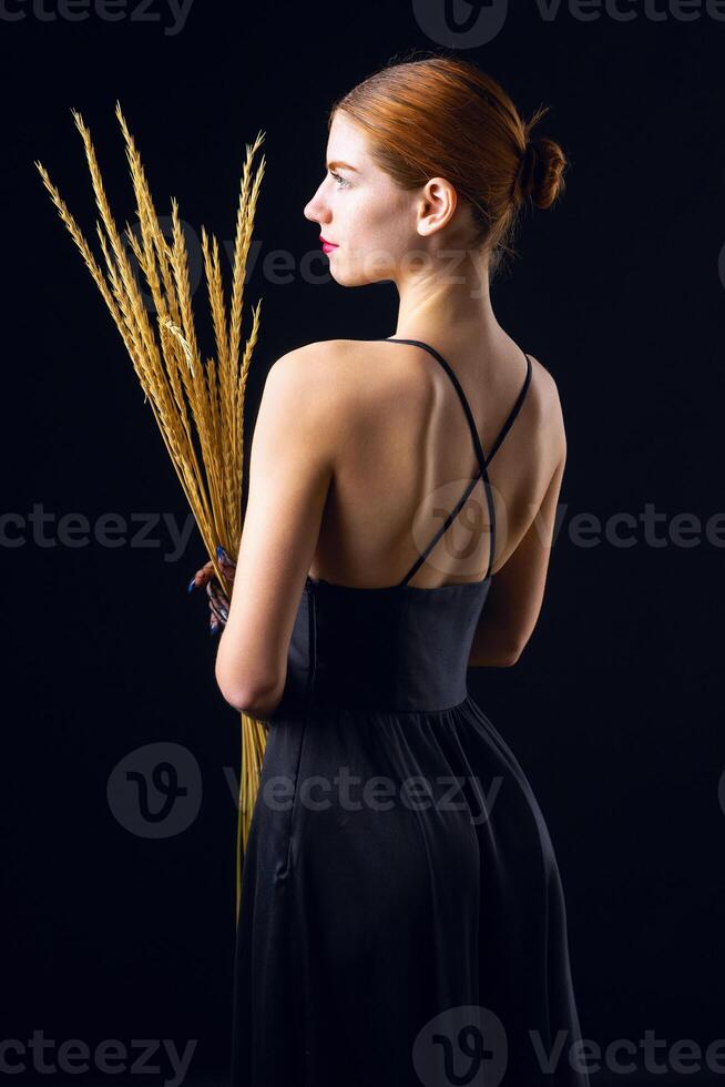 A young redhear girl with clean skin wearing black gloves. Beauty portrait of a woman on a black photo