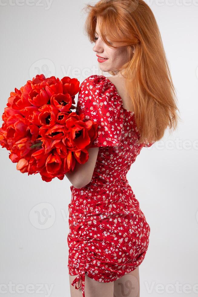 Young happy woman with a bouquet of red lulips. Portrait of a red-haired lady photo