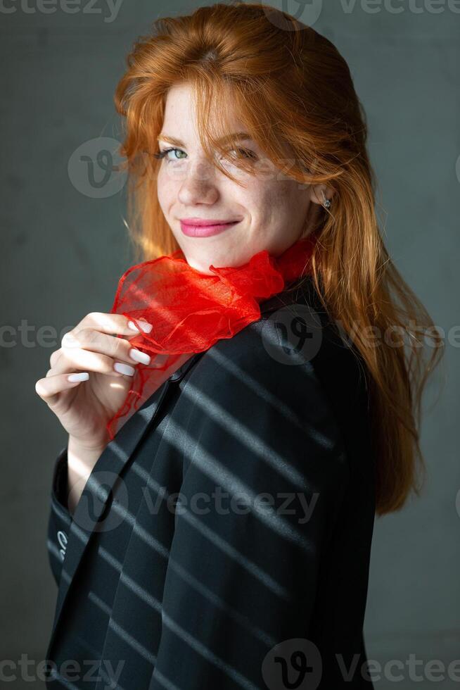 Portrait of a red-haired girl with a red scarf around her neck, in a suit and top photo