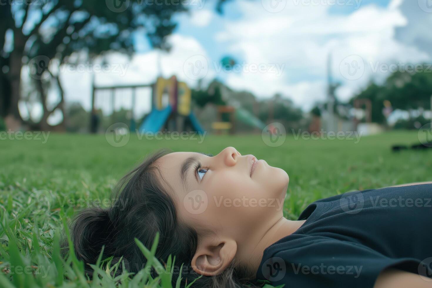 Child lying on the grass, gazing at the sky photo