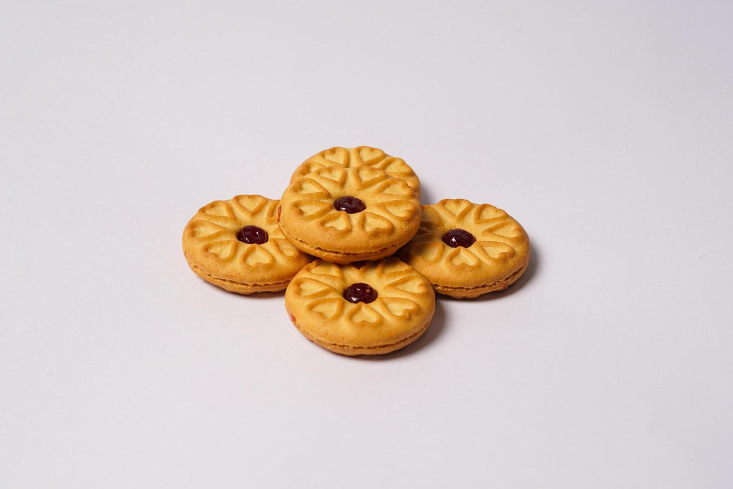 Side view of strawberry jam biscuits on white background, decorated with a circular heart motif on their surface. High resolution photo. photo