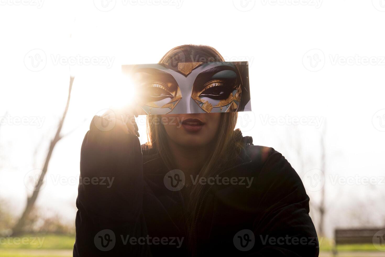 portrait of young woman having fun showing a fantasy image partially covering their face in a public park in winter photo