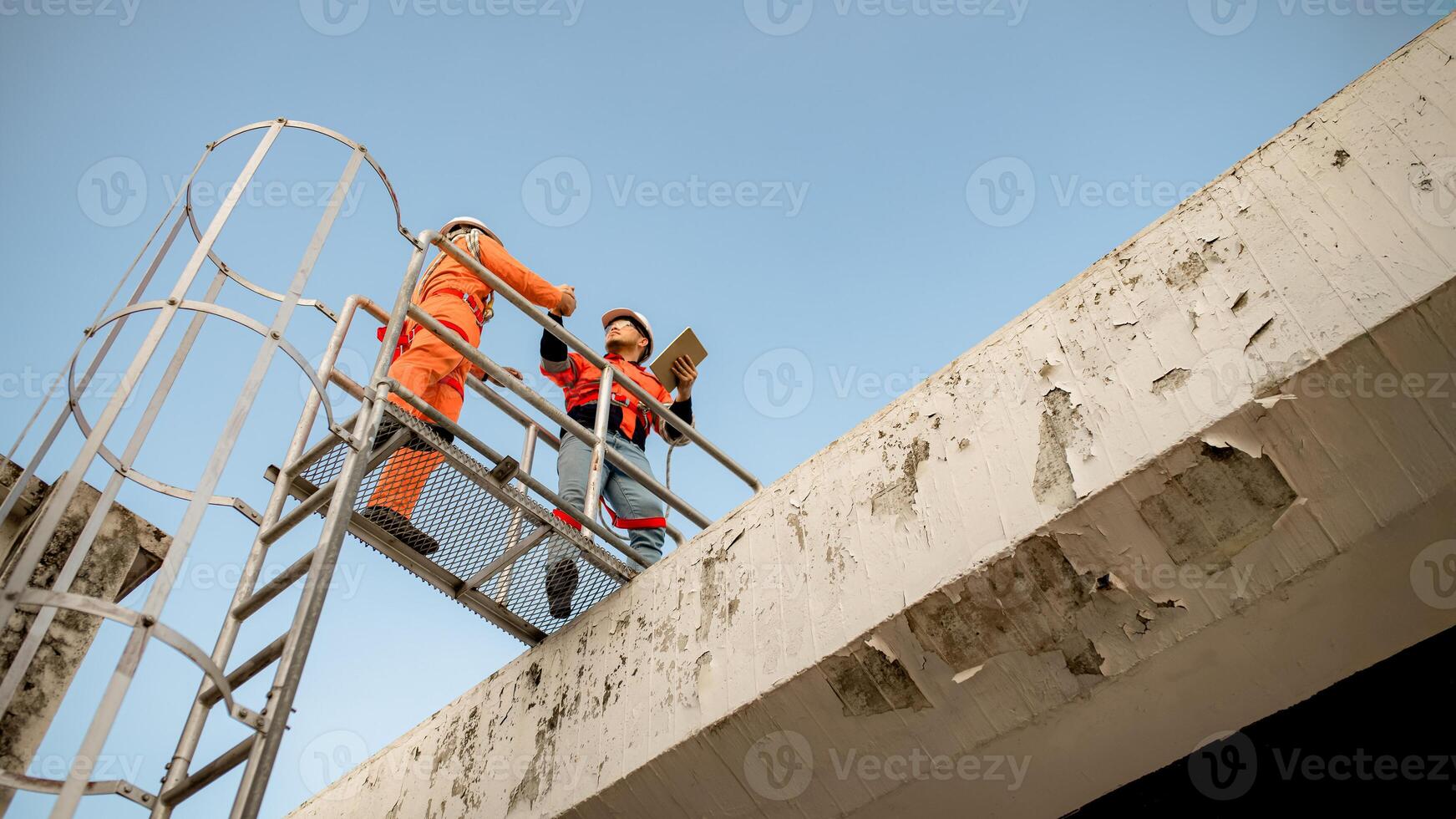 Two maintenance technicians and solar panel installers are planning to install solar cells on the roof of a building. photo