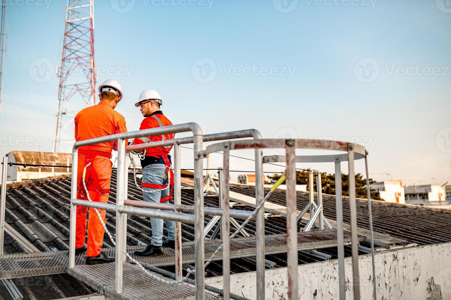 Two maintenance technicians and solar panel installers are planning to install solar cells on the roof of a building. photo