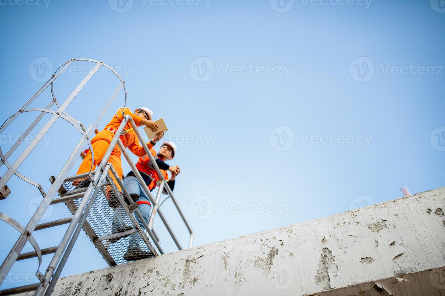 Two maintenance technicians and solar panel installers are planning to install solar cells on the roof of a building. photo