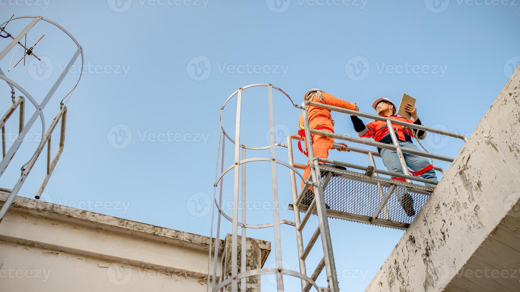 Two maintenance technicians and solar panel installers are planning to install solar cells on the roof of a building. photo