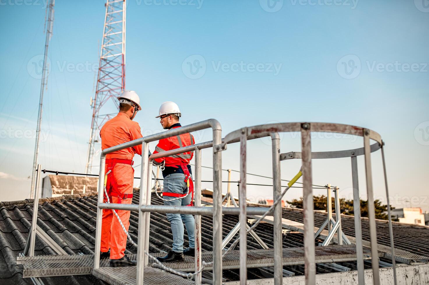 Two maintenance technicians and solar panel installers are planning to install solar cells on the roof of a building. photo