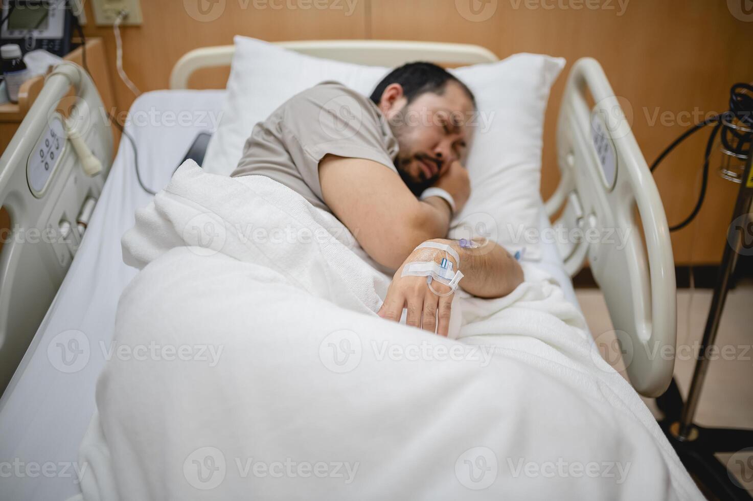 Middle Aged Man Resting Alone in a Hospital Room, Receiving IV Fluids and Medical Care photo