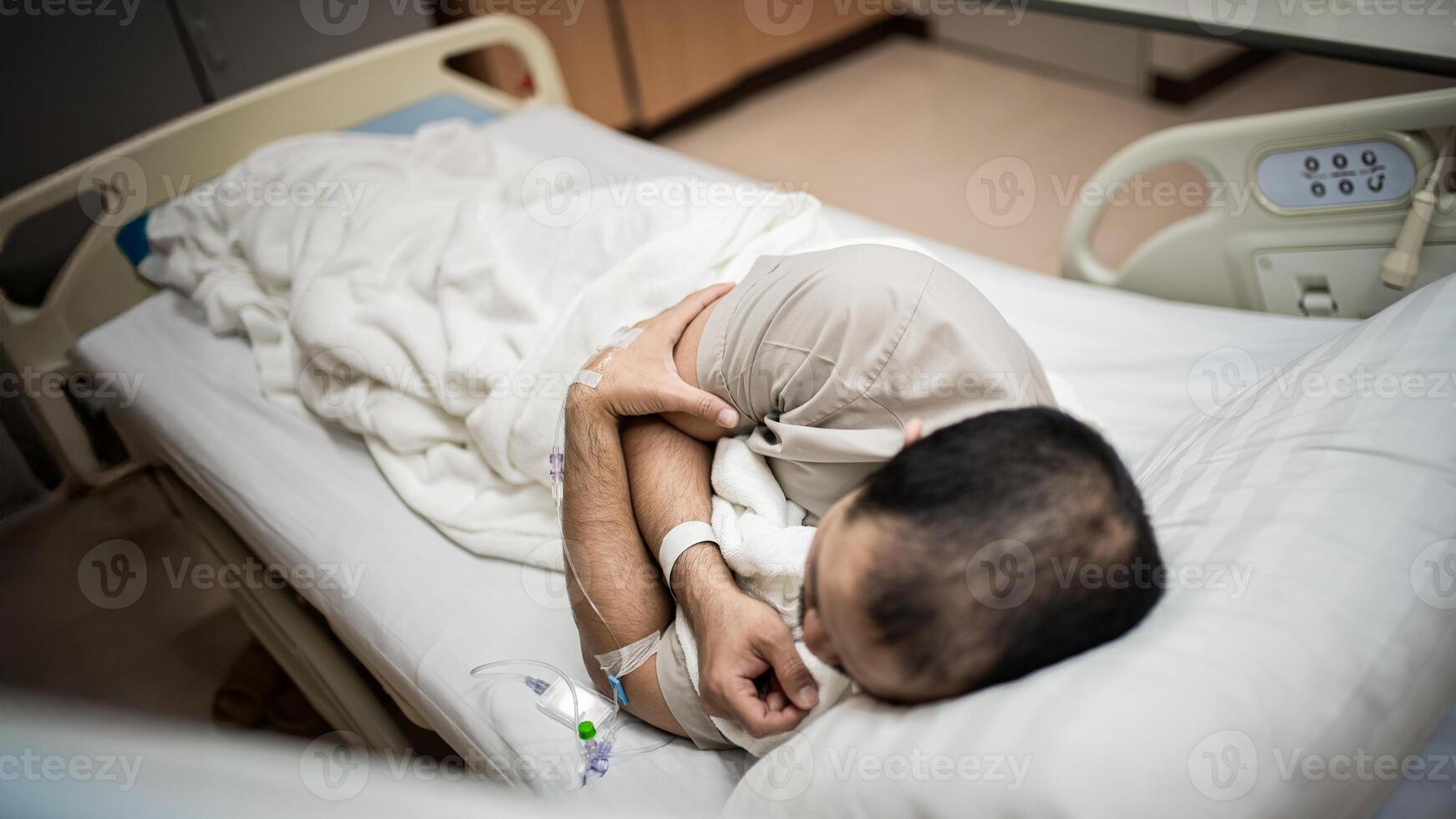 A male patient lies in a hospital room receiving treatment, exhausted and lonely. photo