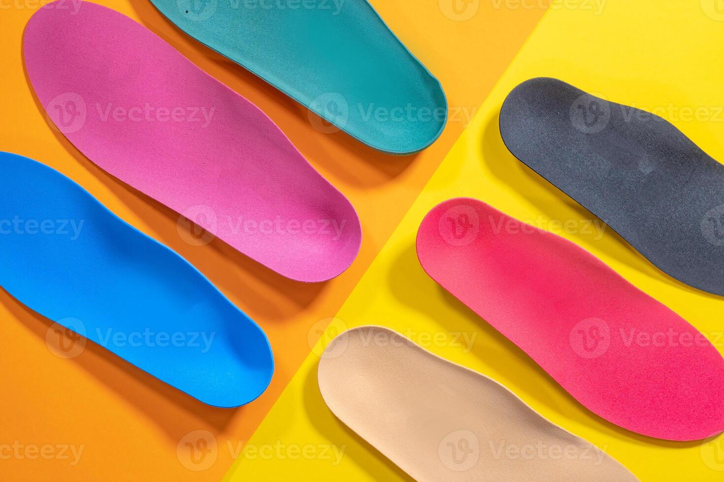 Orthopedic insoles are lined up on a wooden surface. samples of different orthopedic insoles. insoles with a variety of coating. photo
