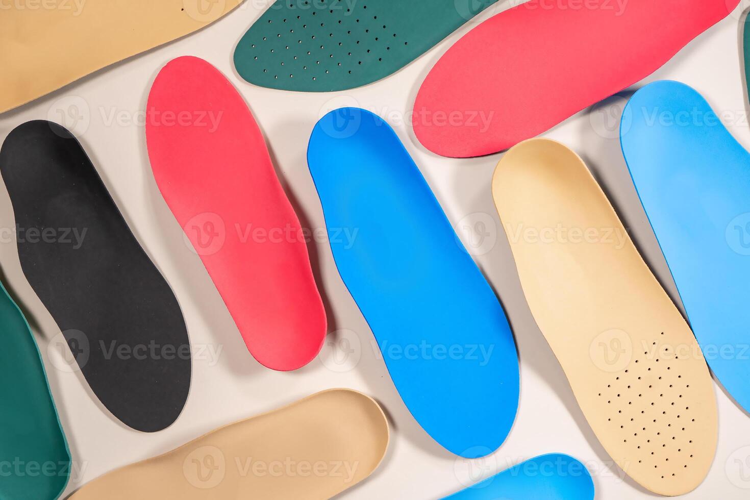 Orthopedic insoles are lined up on a wooden surface. samples of different orthopedic insoles. insoles with a variety of coating. photo