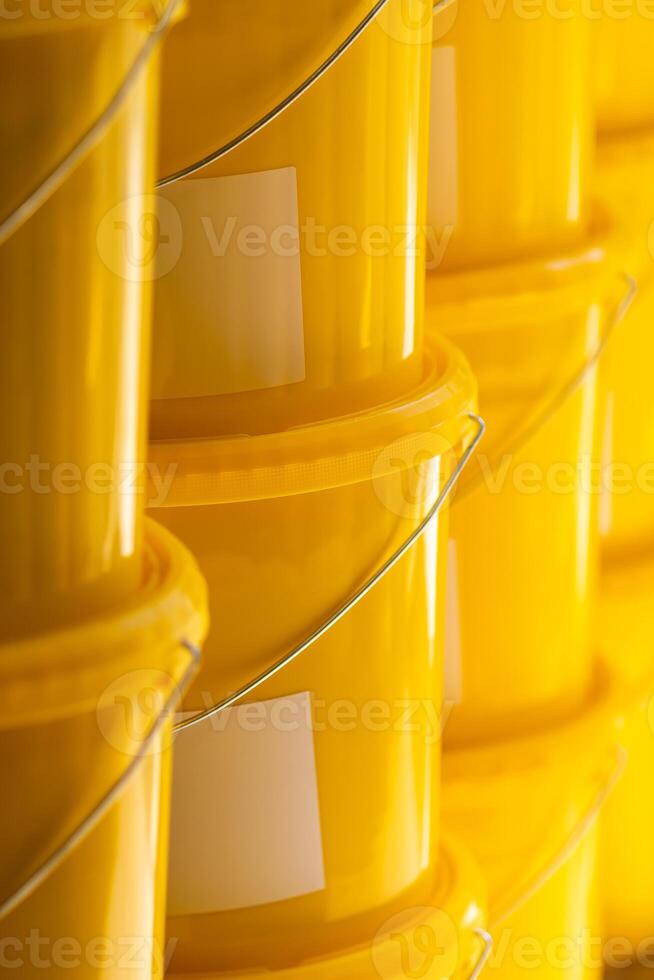 Many yellow color buckets cans in a row with ink paint row photo