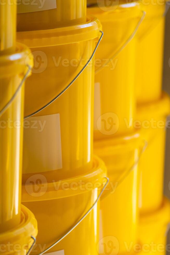 Many yellow color buckets cans in a row with ink paint row photo