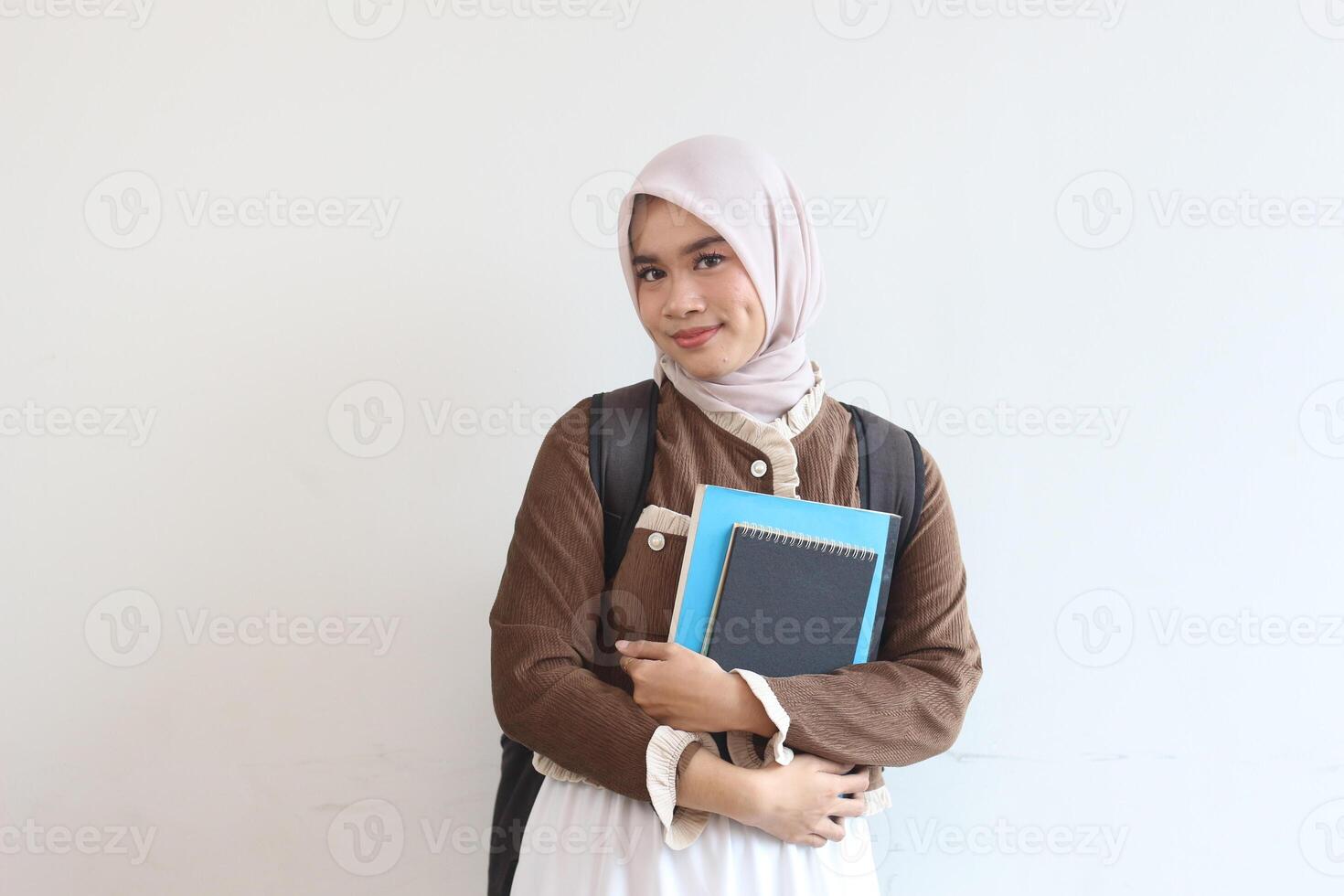 Portrait of a Smiling Muslim Female Student Holding Books Against White Background photo