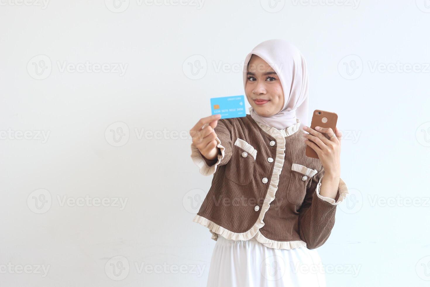 Smiling Woman in Hijab Makes Online Payment with Credit Card and Smartphone photo