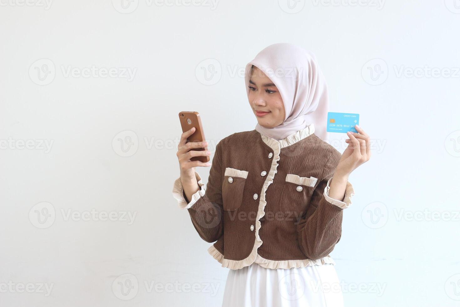 Young Muslim Woman Online Shopping Using Smartphone and Credit Card, Modern Islamic Fashion, E-commerce photo