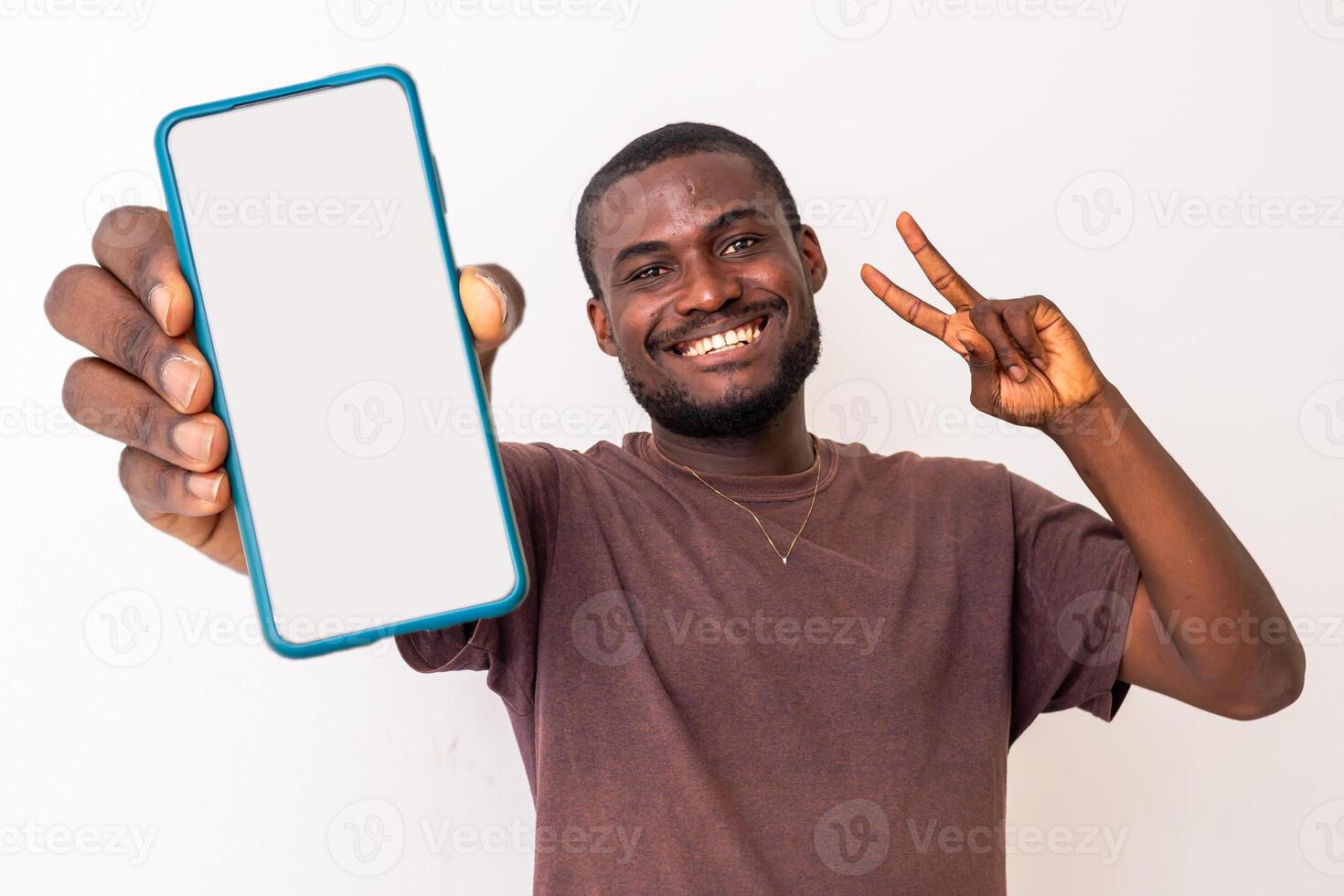 Portrait of excited black African american guy holding big smartphone with white blank screen in hand photo