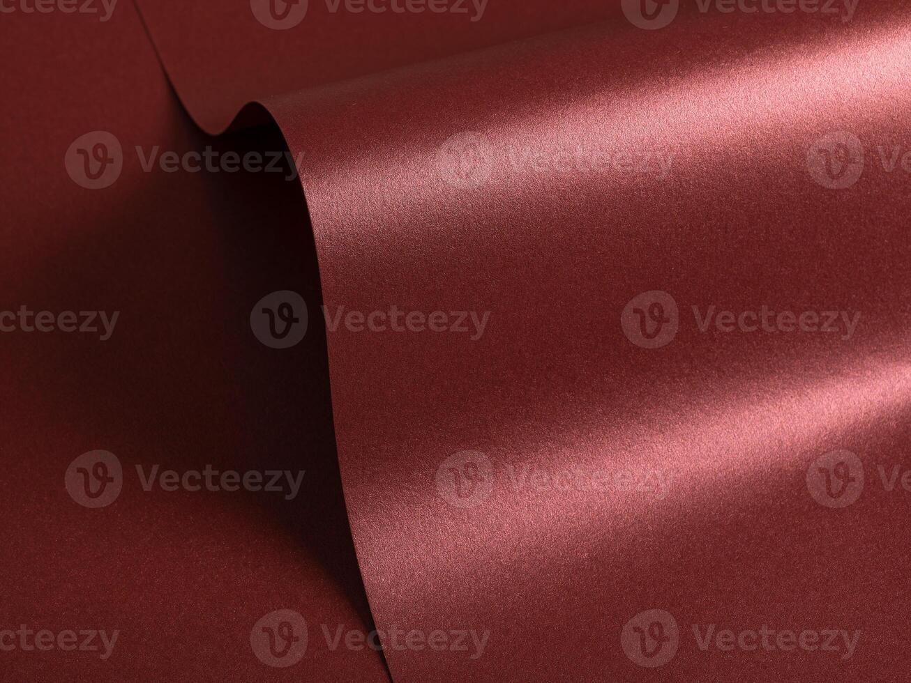 Burgundy red metallic paper texture with a pearlescent sheen and wavy shapes. The glossy satin photo