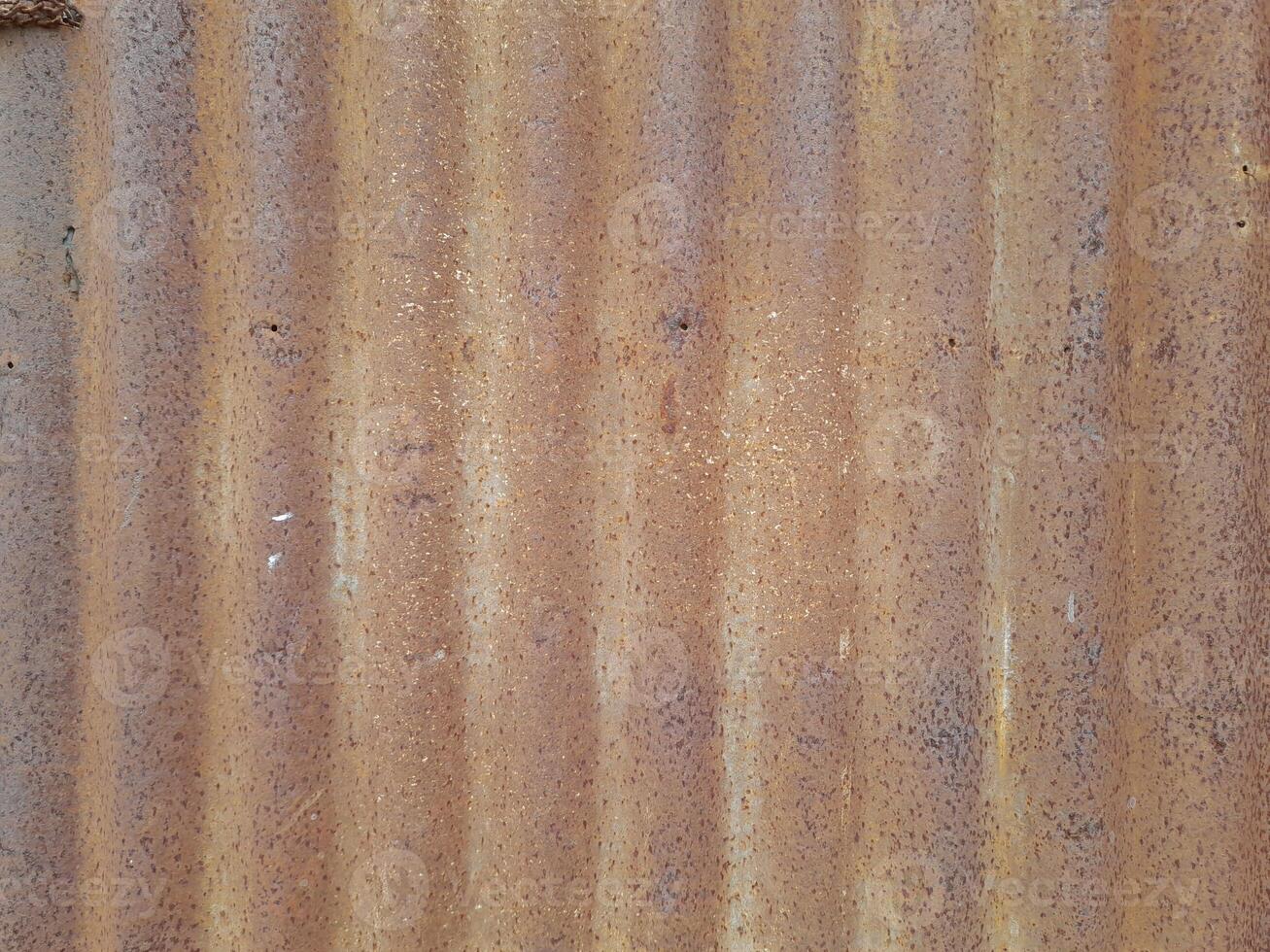 a close-up view of a textured surface a metal sheet, with a dull grayish tone. The surface features a mix of light and dark patches, creating a mottled, weathered, or oxidized appearance photo