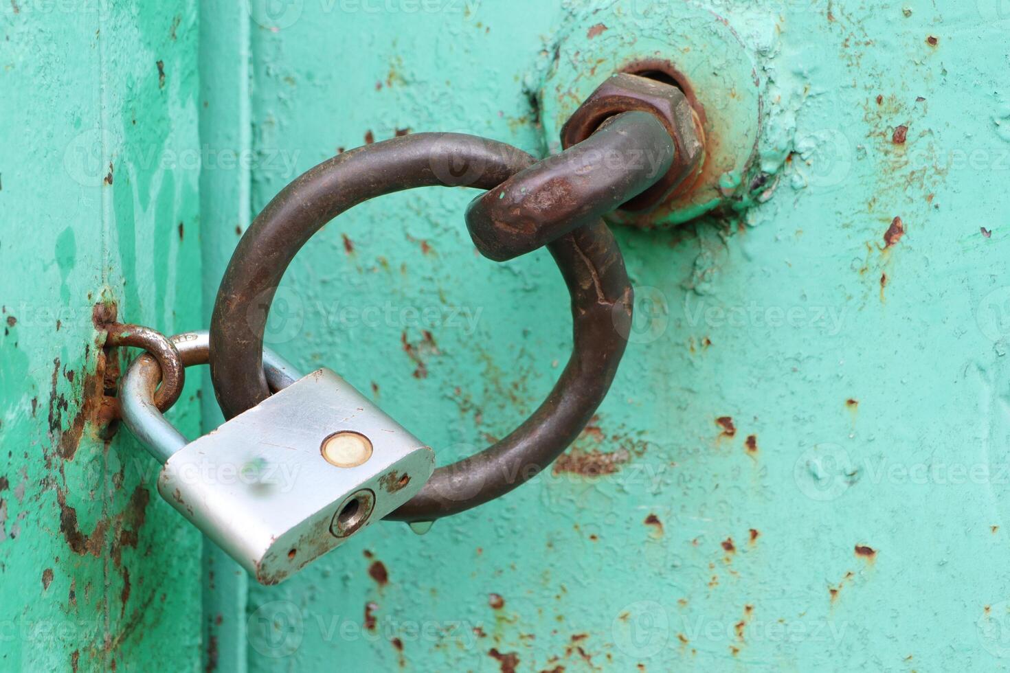 An old, rusty lock attached to a vibrant turquoise door, a fascinating sight to behold photo