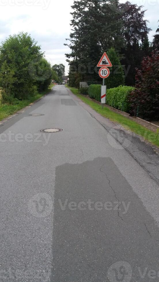 A peaceful and tranquil quiet rural road featuring a yield sign surrounded by lush greenery photo