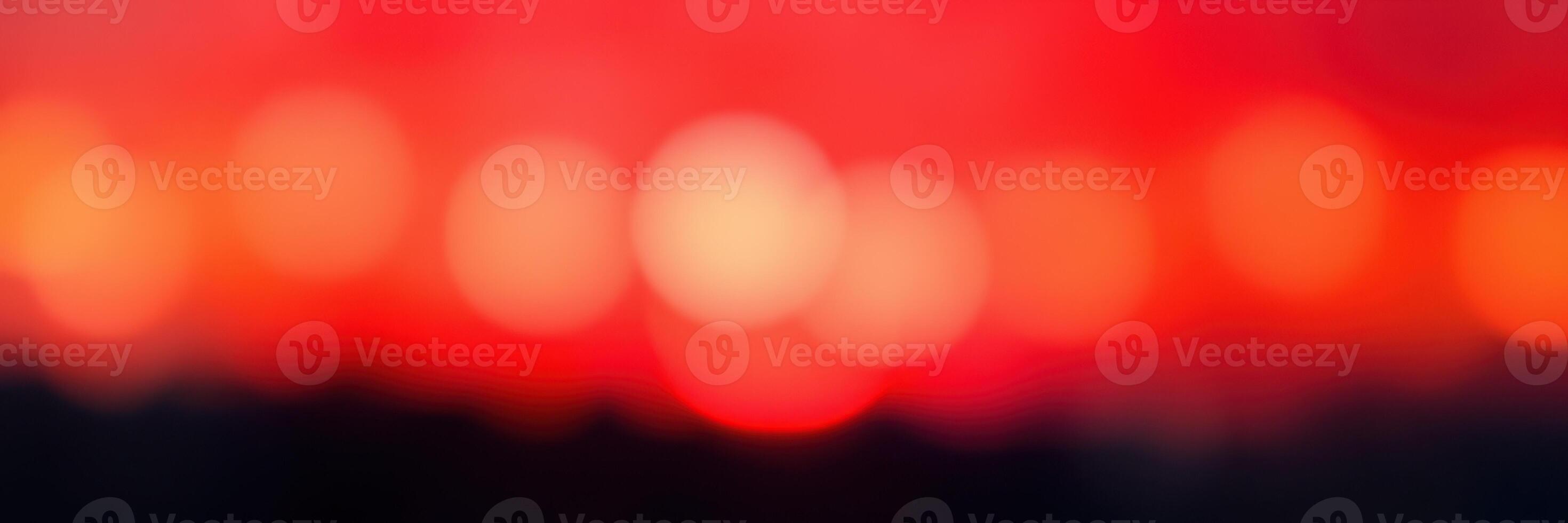 Sunset creates vibrant bokeh of red and orange hues over a tranquil landscape with glowing lights photo