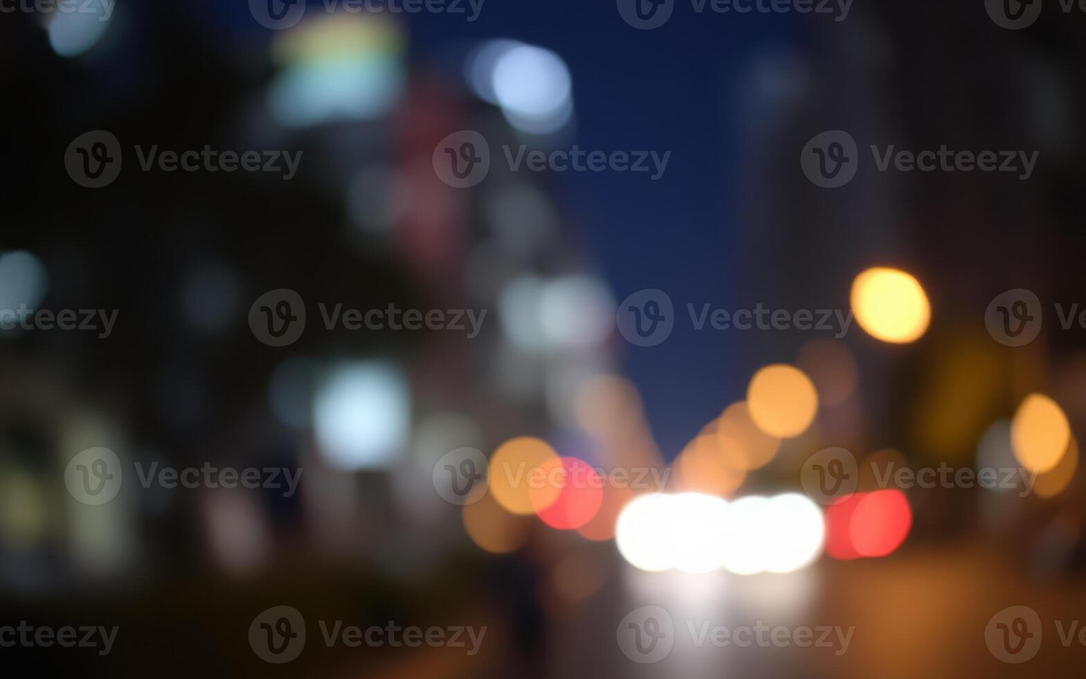 City lights illuminate a blurred urban street at night, showcasing the vibrant energy of the city after dark photo