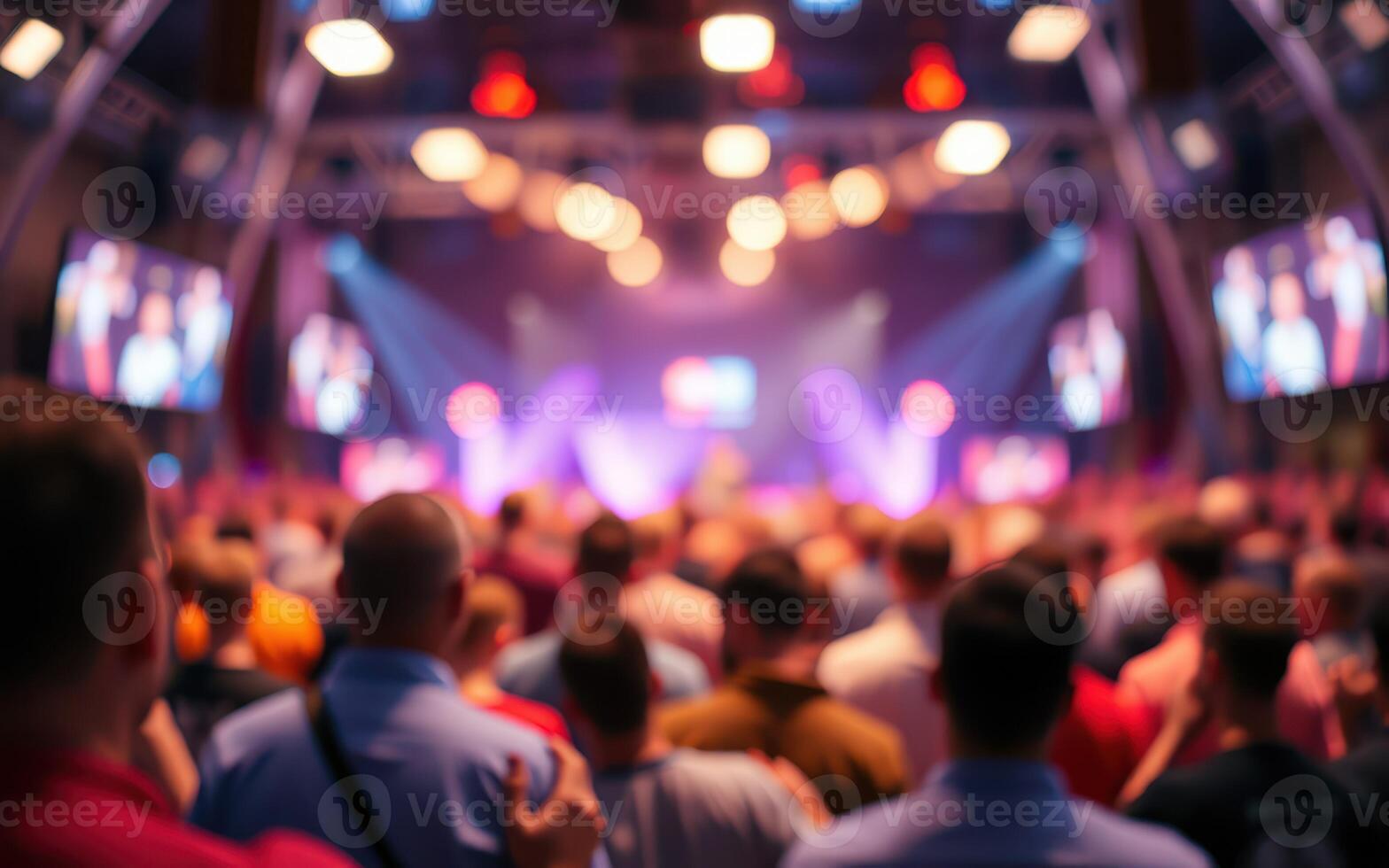 Crowd gathers in excitement during a vibrant event at a modern venue featuring colorful lights and large screens photo