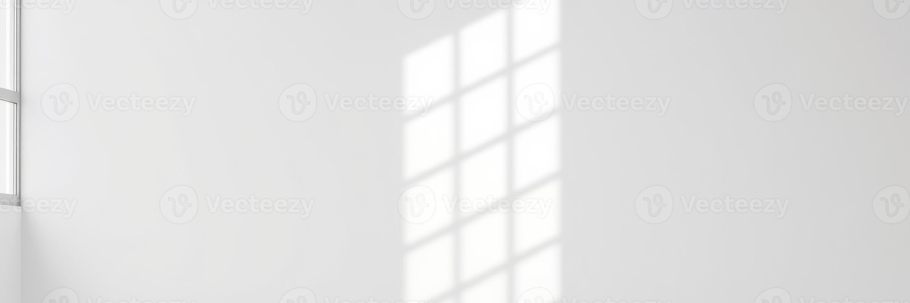 Bright sunlight streaming through a window casts a patterned shadow on a minimalist wall space photo