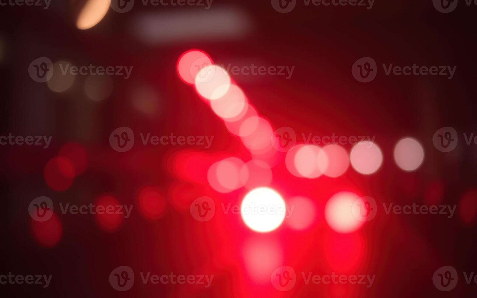 Colorful bokeh lights illuminate a city street during nighttime with a vibrant red hue creating an abstract urban landscape photo