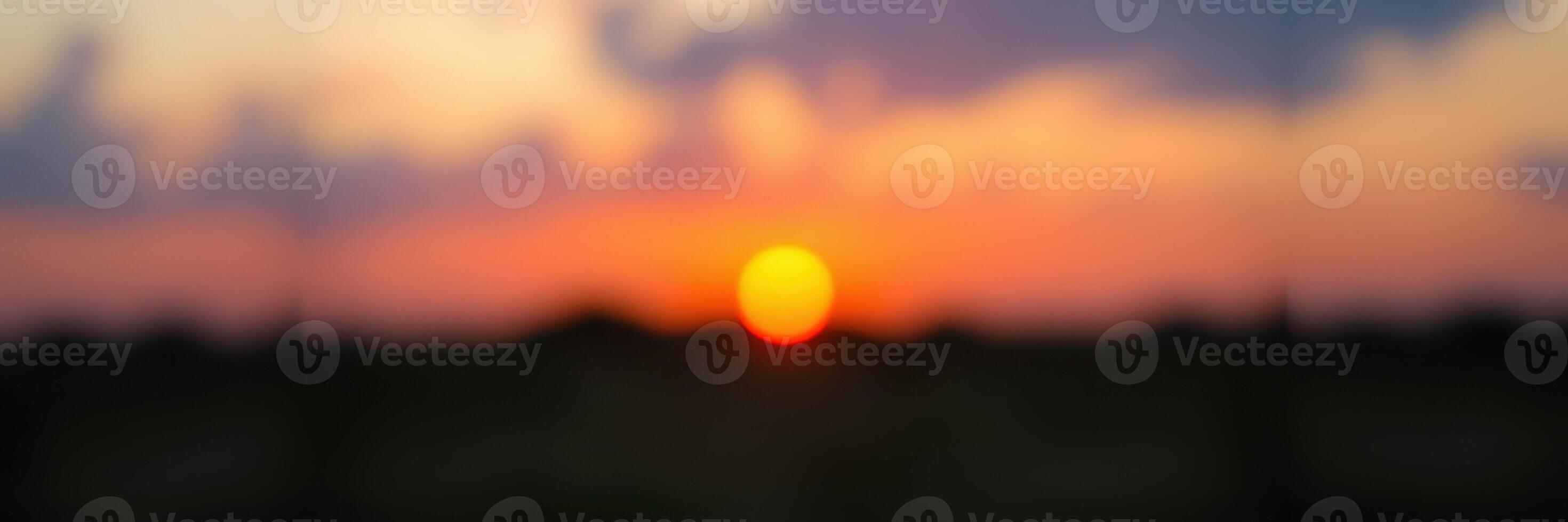 Sunset over a tranquil field with vibrant colors and soft clouds on a peaceful evening photo