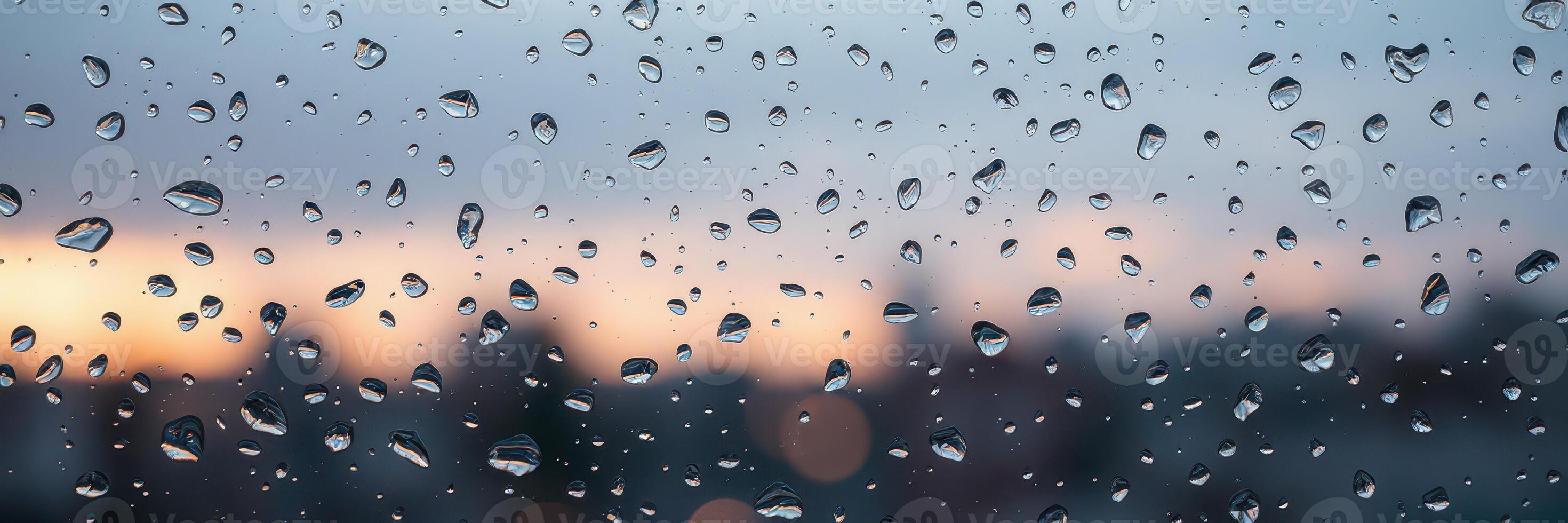 Rain droplets on a window with a blurred city skyline and twilight colors in the background photo