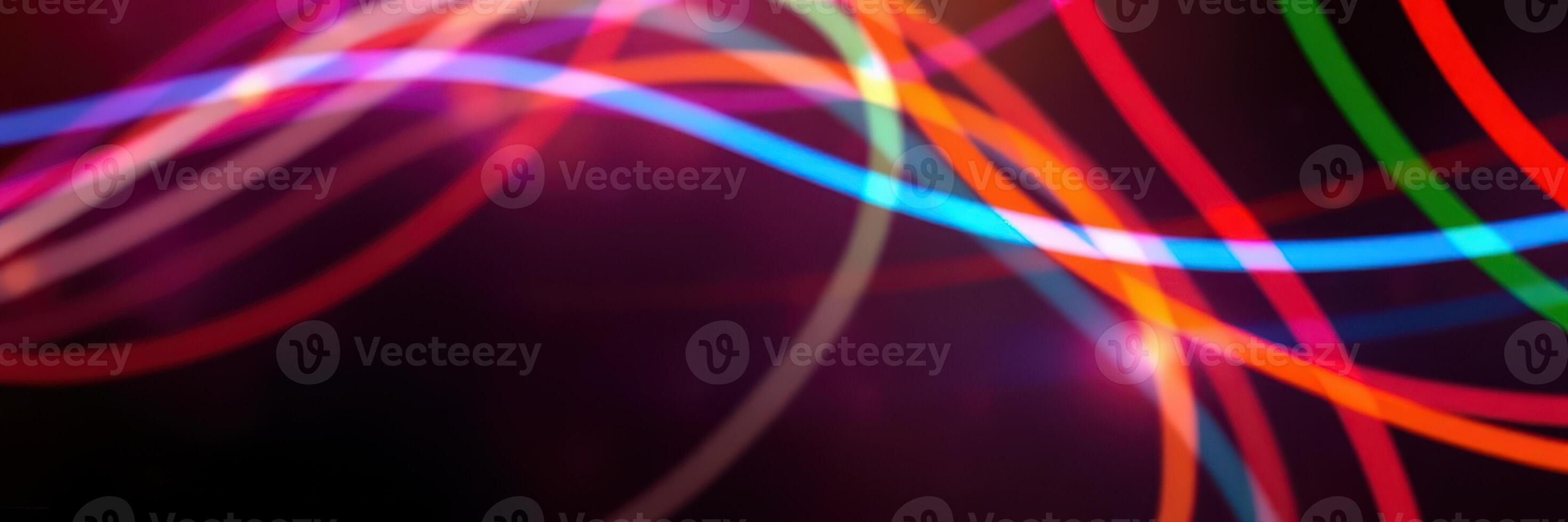Colorful light trails swirl through a dark background creating a dynamic abstract pattern on a vibrant night photo