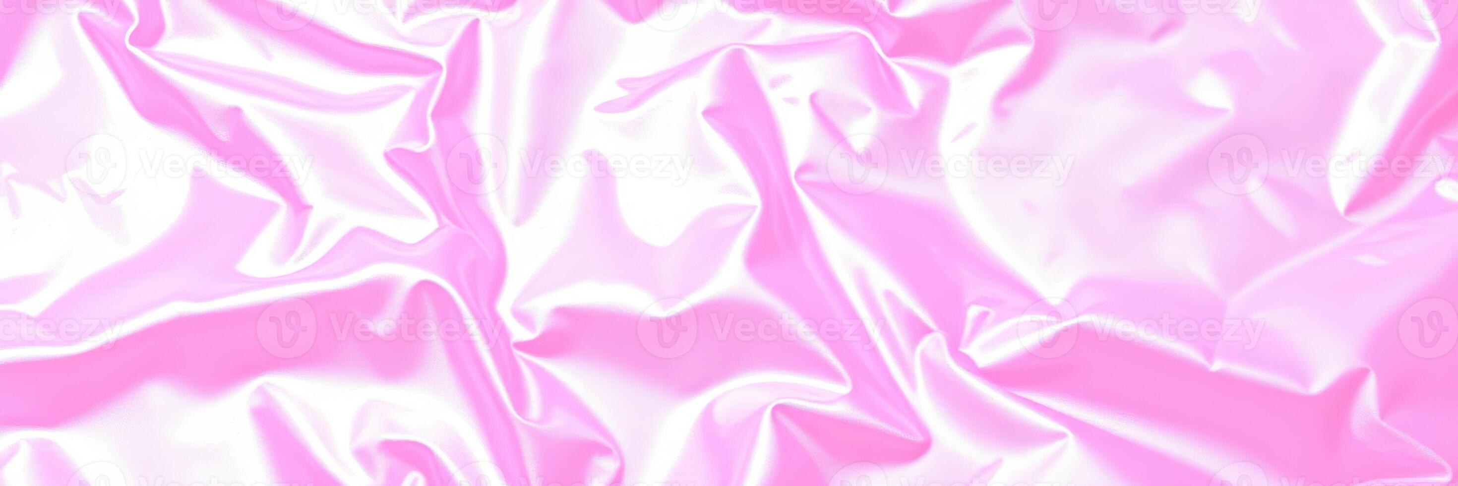 Wrinkled shiny pink fabric creating a soft and glossy texture under soft lighting in a playful arrangement photo