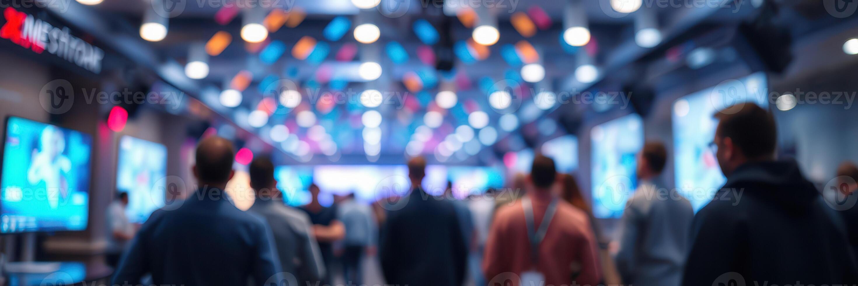 Crowd of attendees engaged at a modern conference venue with digital displays in the background photo