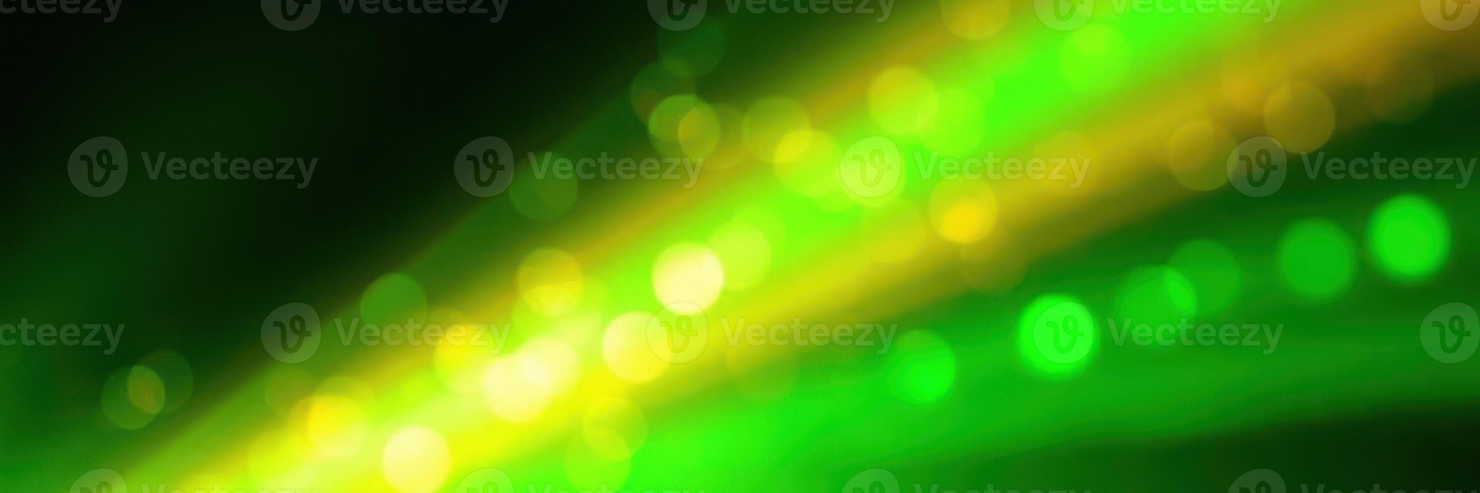 Vibrant green and yellow light streaks create an abstract visual display at a nighttime event photo
