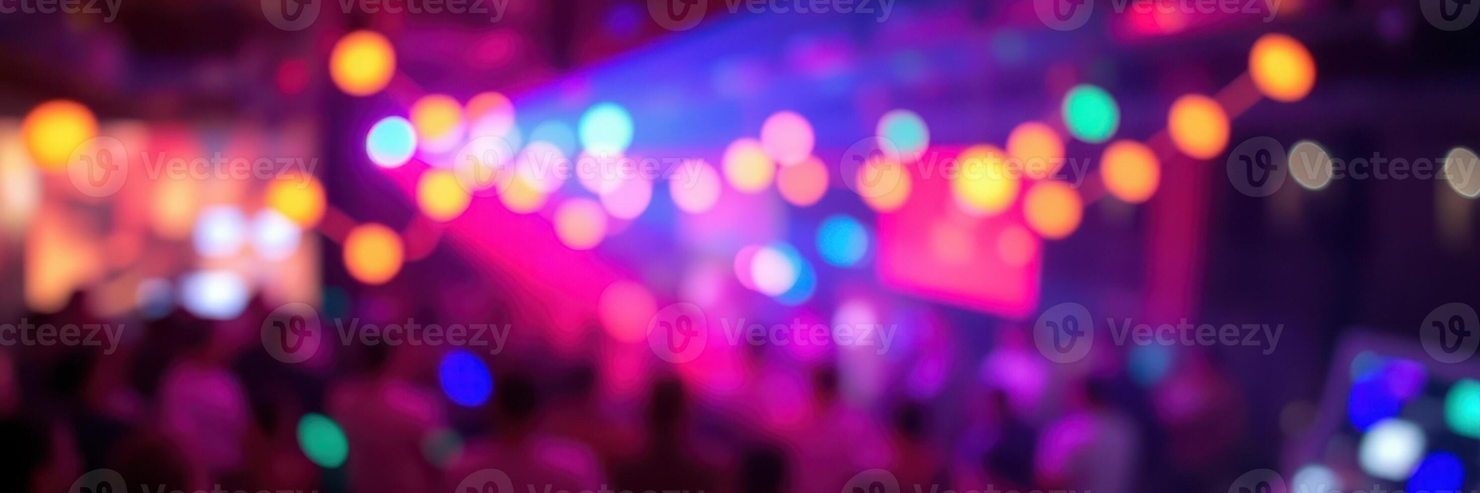 Colorful lights illuminate a lively indoor celebration with a crowd enjoying music and dancing late into the night photo