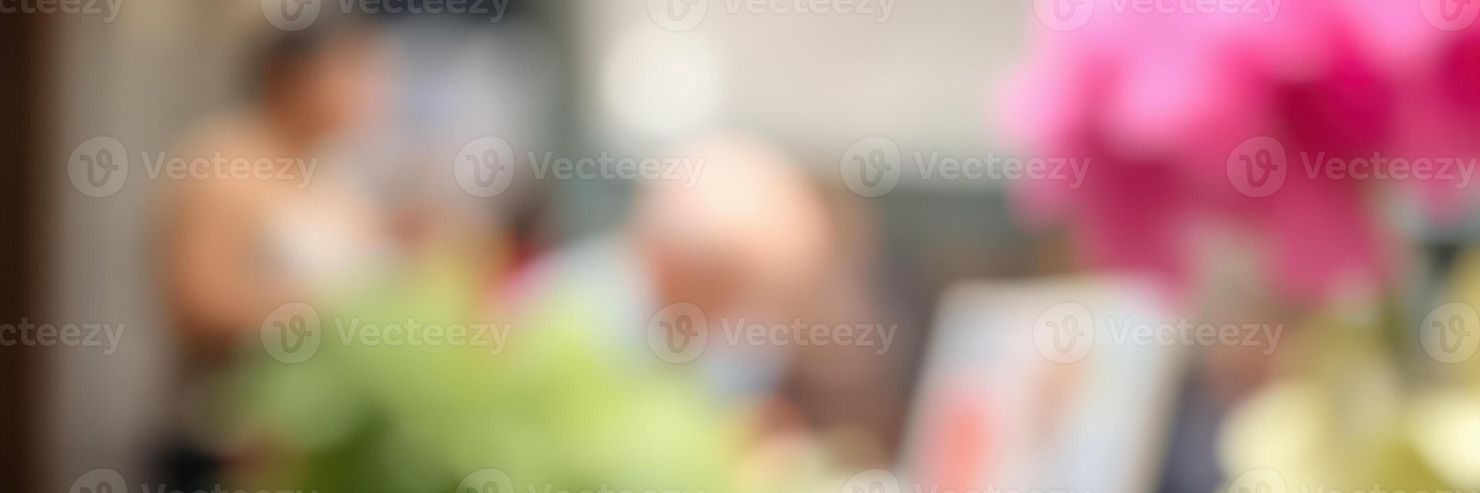 Group of people enjoying a lively conversation in a cafe with pink flowers in focus photo
