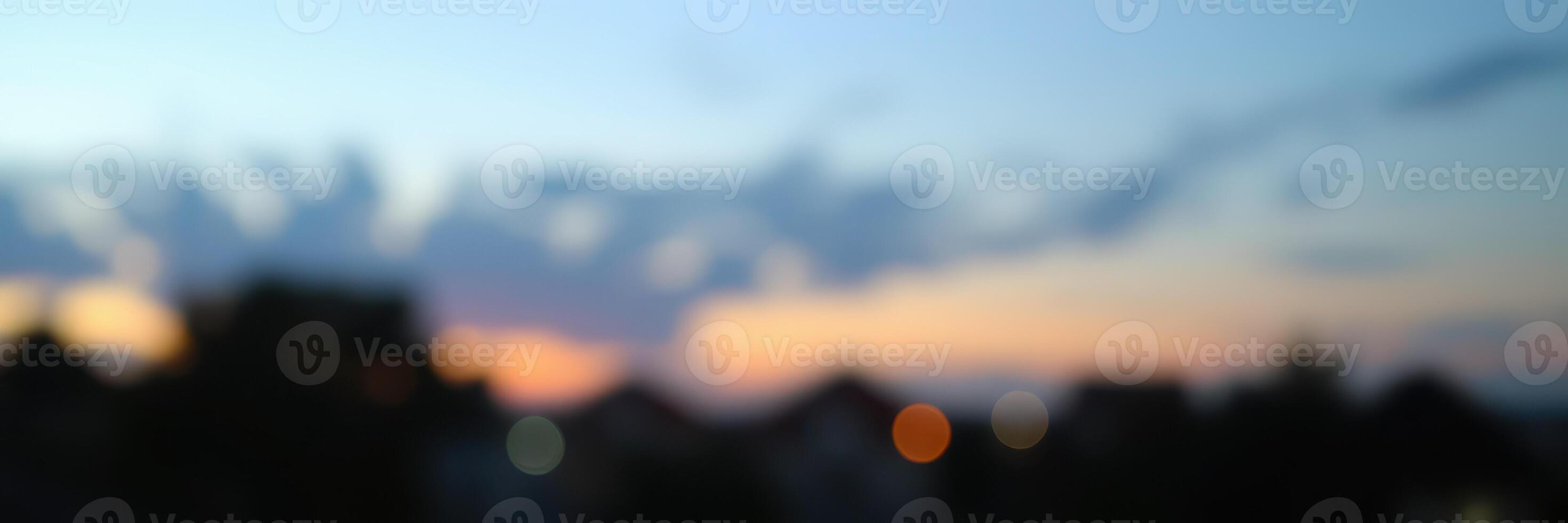 Colorful sunset casts a gradient across the sky with silhouetted buildings in the foreground during evening hours photo