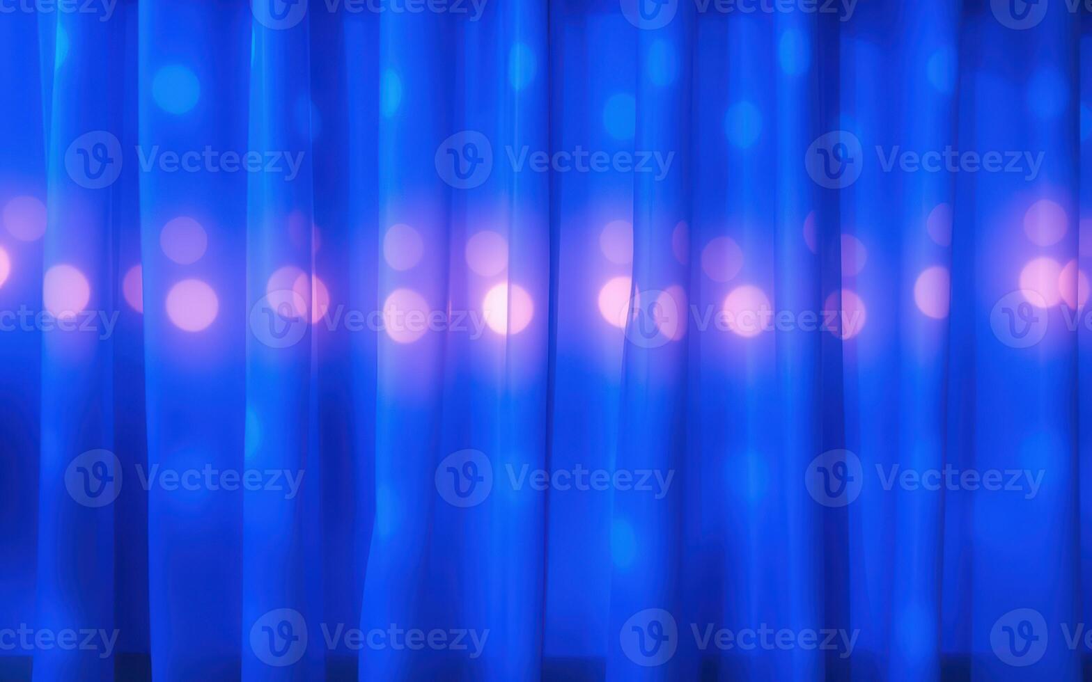 Light reflections and blurred blue curtains create an artistic backdrop for an event during the evening in a cozy venue photo