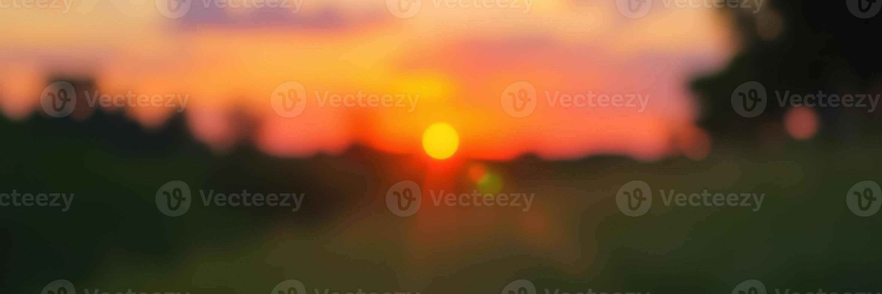 Beautiful sunset over a serene landscape with vibrant colors and soft silhouettes of trees photo