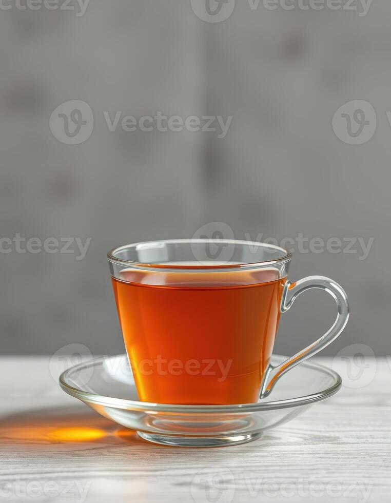 Clear glass cup filled with hot tea on a white wooden table in a softly lit environment photo