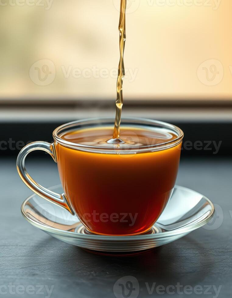 Enjoying a warm cup of tea poured into a glass vessel near a window during a peaceful afternoon moment photo