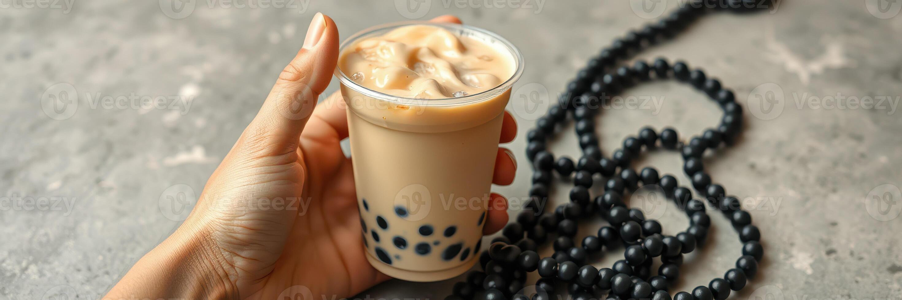 Enjoying a refreshing bubble tea with tapioca pearls and a necklace on a textured surface in a bright setting photo
