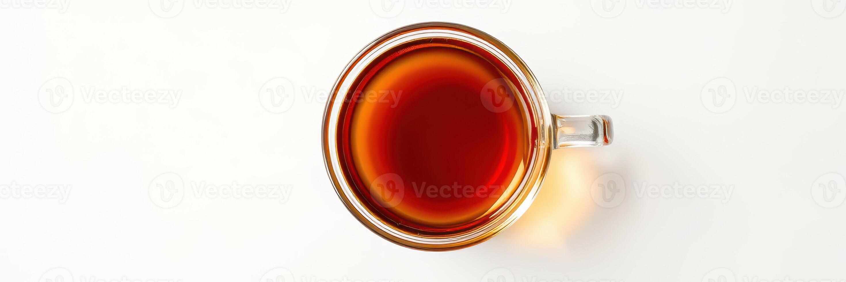 Warm cup of brewed tea resting on a white surface with rich amber color visible photo
