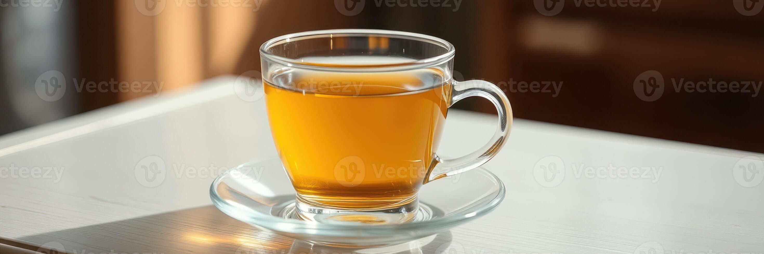 Warm herbal tea in a clear glass cup served on a small saucer on a wooden table in a cozy setting photo