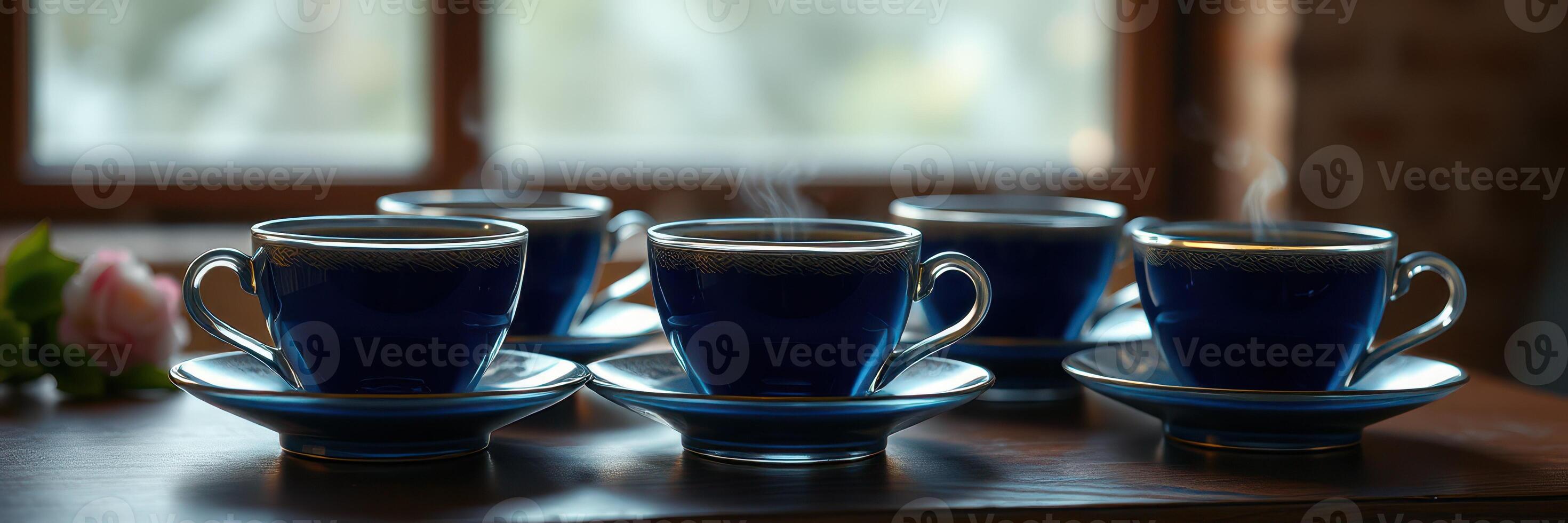 Five steaming blue cups of coffee arranged on a wooden table near a window with soft natural light photo
